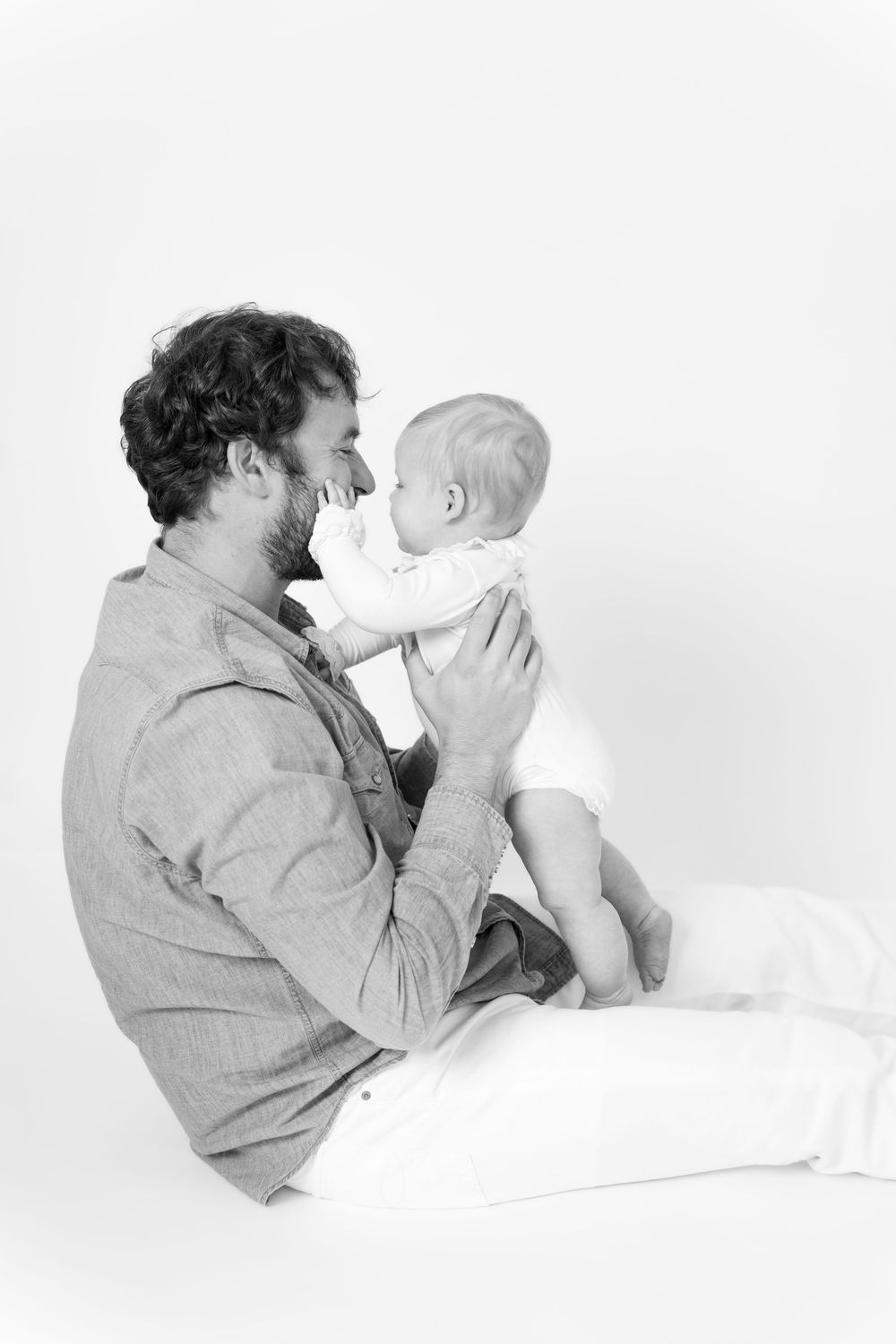 Series of black and white photos showing tender moments between parent and baby in profile against white background.