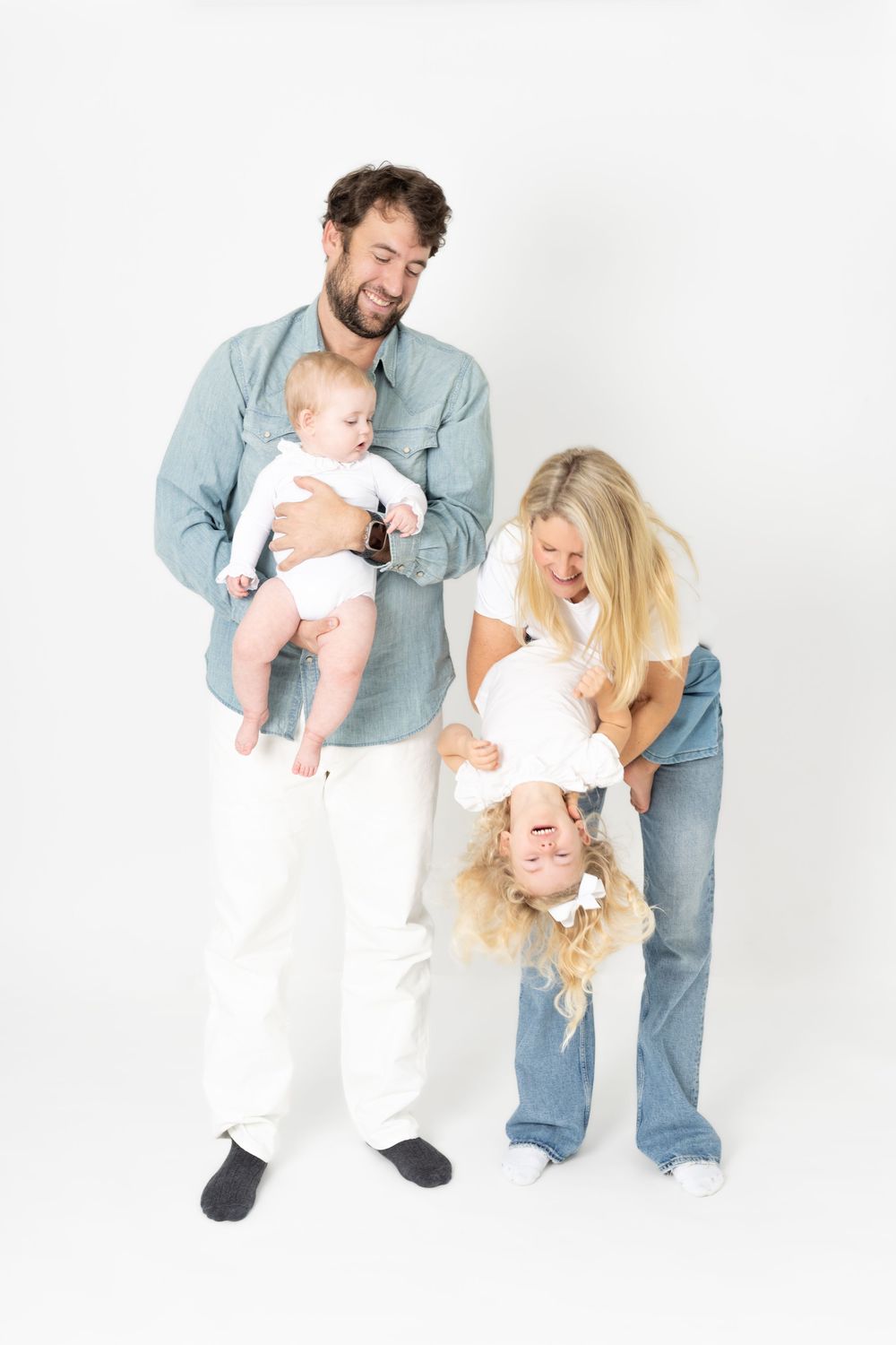 A series of playful family portraits showing parents and baby in white outfits against a light background.