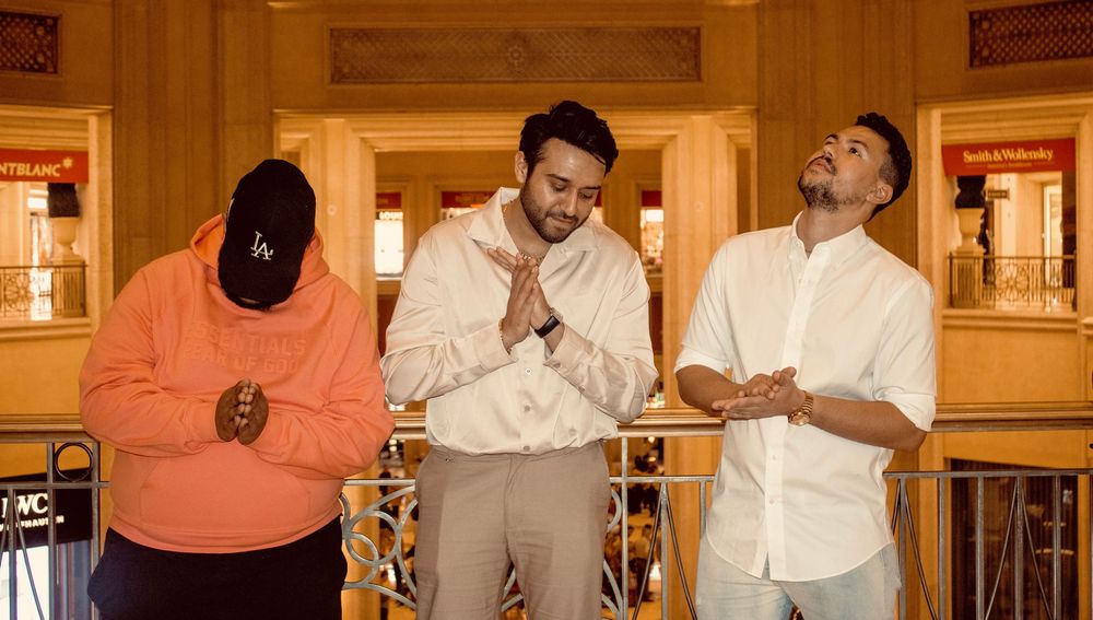 Three men pose playfully on balcony inside The Venetian Las Vegas resort.