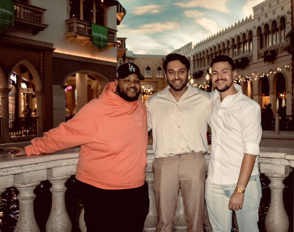 Three smiling men pose together at The Venetian Las Vegas resort interior.