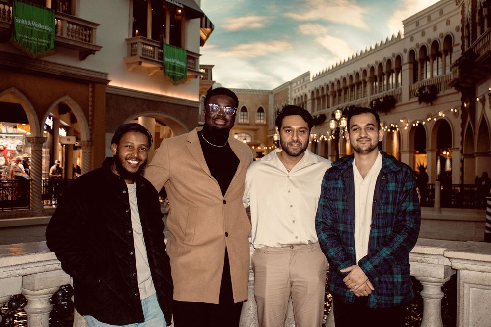 Four men smiling together at night outside The Venetian Las Vegas hotel.