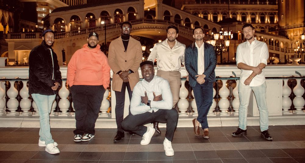 Group of seven men posing together at The Venetian Las Vegas with one crouching center.