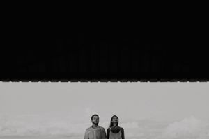 Minimalist black and white portrait of couple standing together beneath dark sky. Fotógrafo de Bodas en Formosa