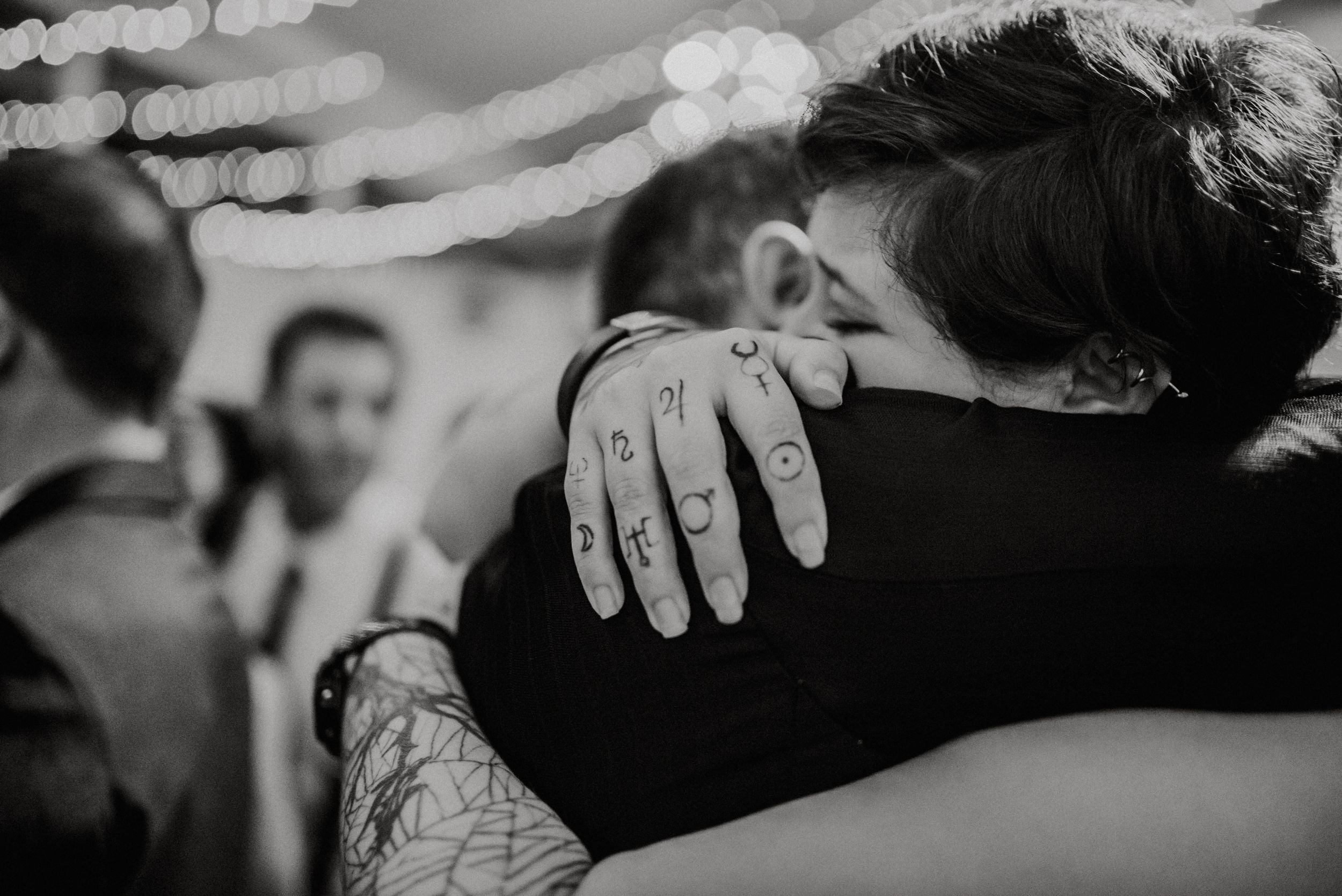 Black and white close-up of tattooed hands embracing at a wedding reception. Fotógrafo de Bodas en Formosa