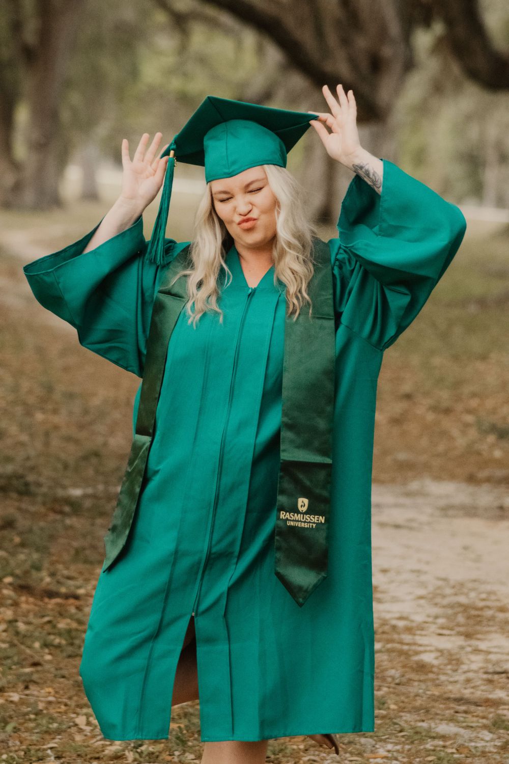 Graduate in emerald green cap and gown poses playfully in a series of outdoor photos during graduation photoshoot.