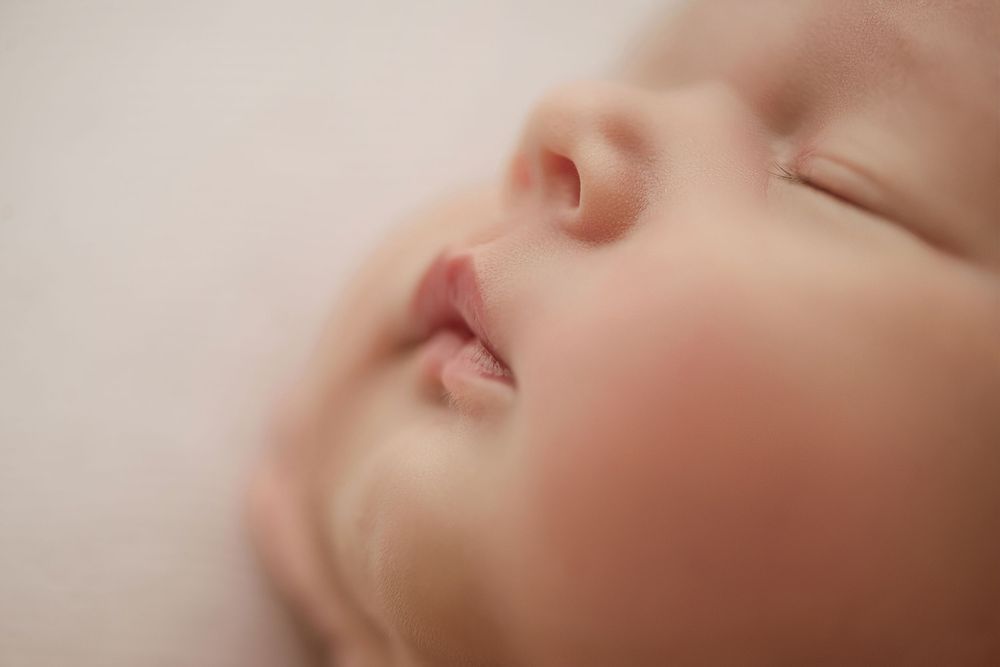 Close up macro photo of a sleeping baby's face with soft focus and dreamy lighting.