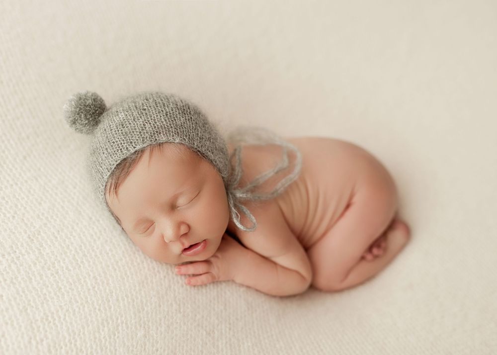 A series of minimalist newborn photography portraits showing a sleeping baby in different curled positions on white fabric.