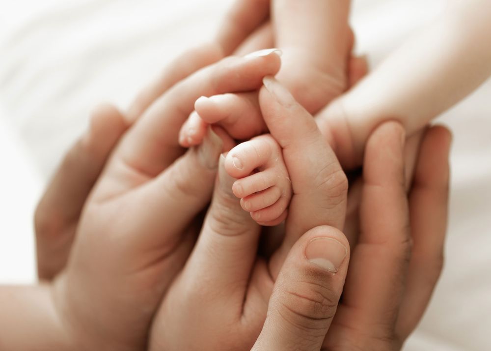 Baby's tiny hand gently grasps an adult's finger in a tender moment of connection and trust.