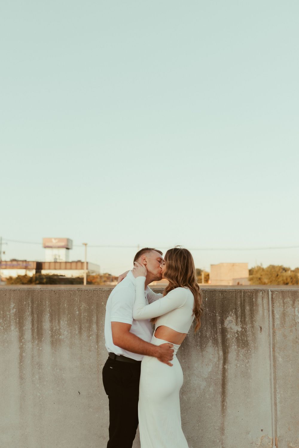 Romantic couple embracing on urban rooftop during golden hour.