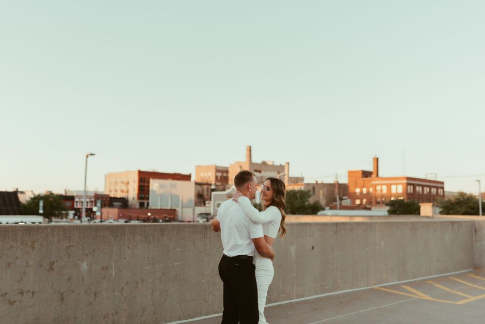 Couple in formal attire dancing on city rooftop at dusk.