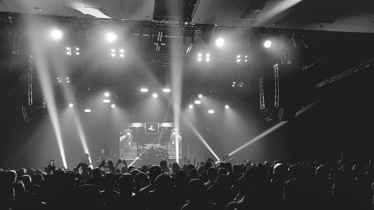 Music concert venue with dramatic spotlights and crowd silhouettes in black and white.