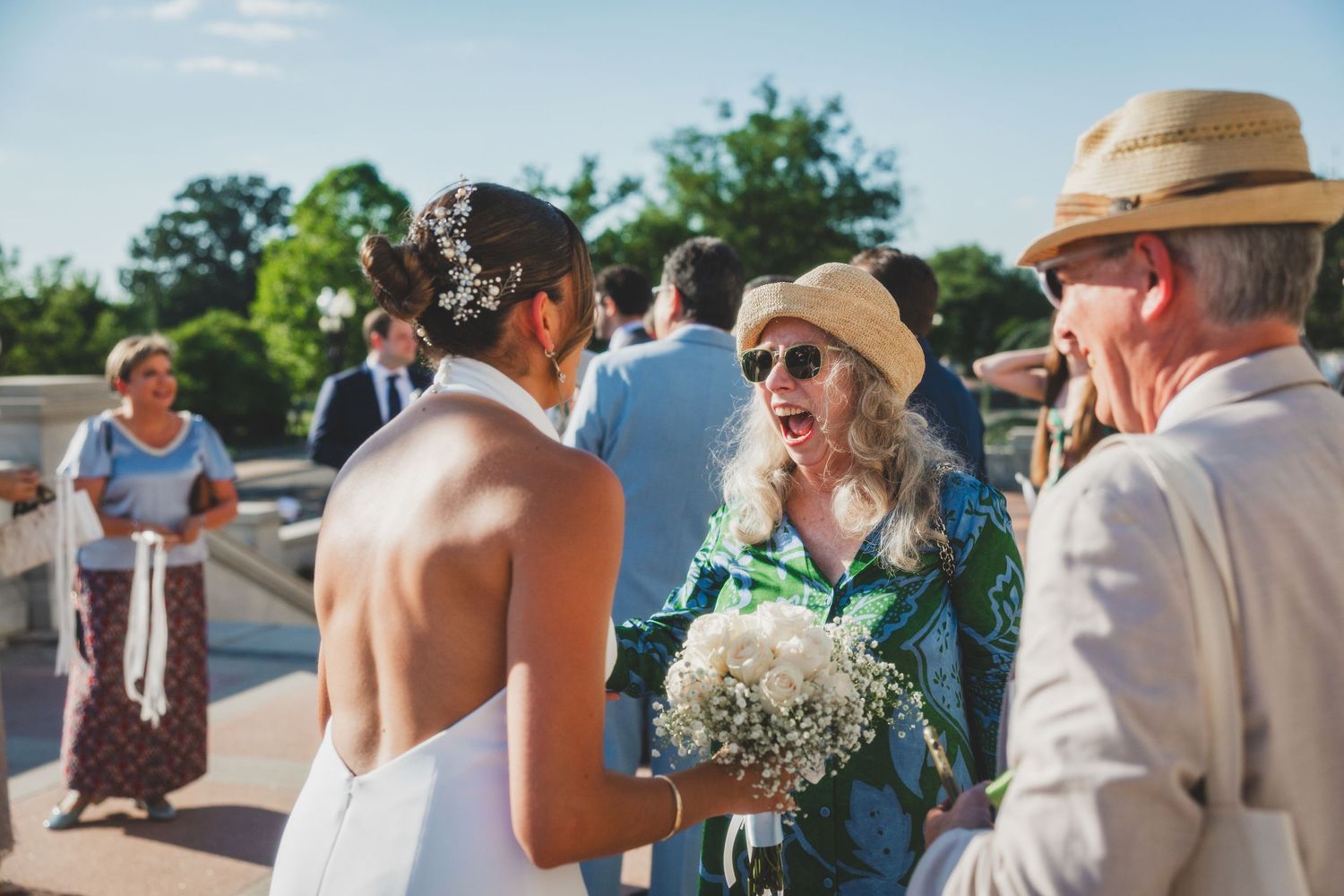 Wedding guests chat and celebrate on steps of historic building.
