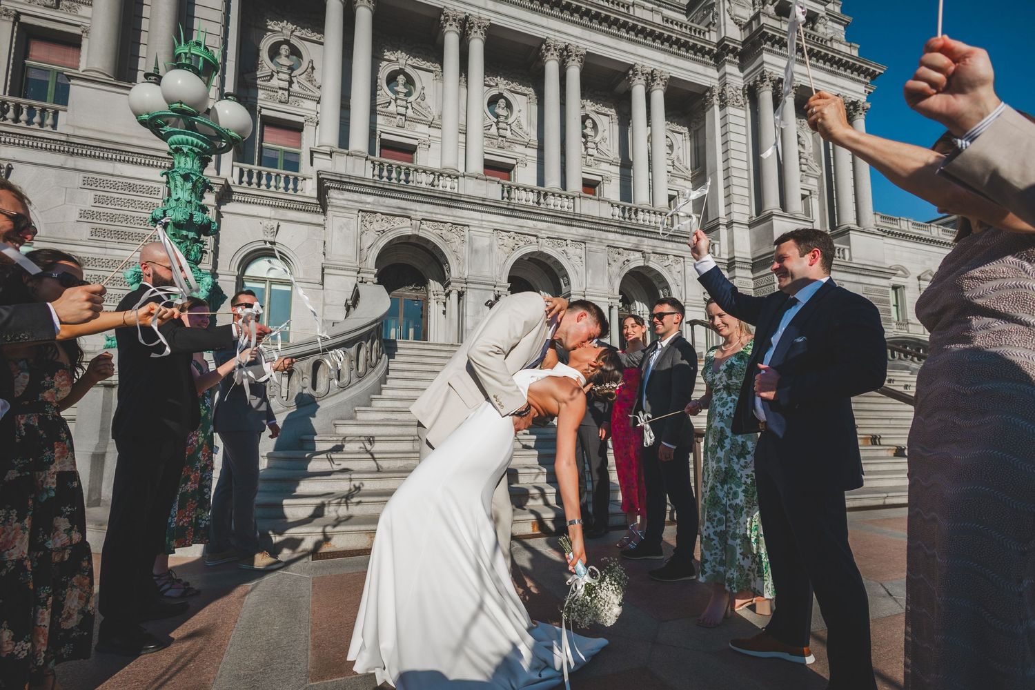 Wedding celebration on historic building steps with guests cheering dramatic pose.