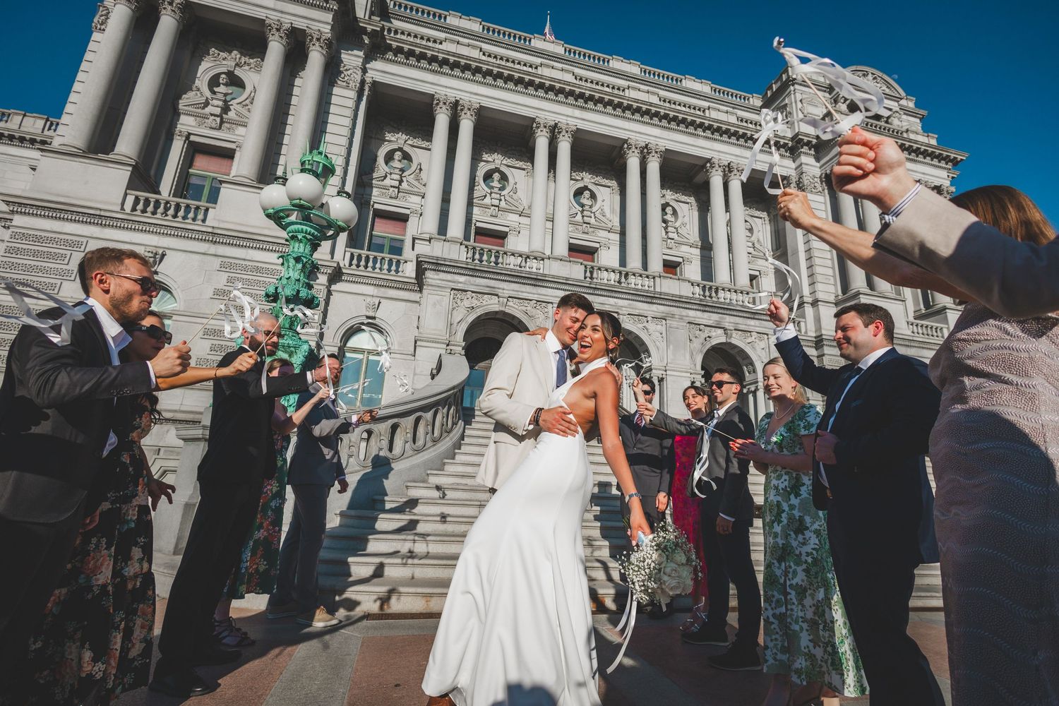 Wedding celebration with guests blowing bubbles on the steps of a grand historic building.