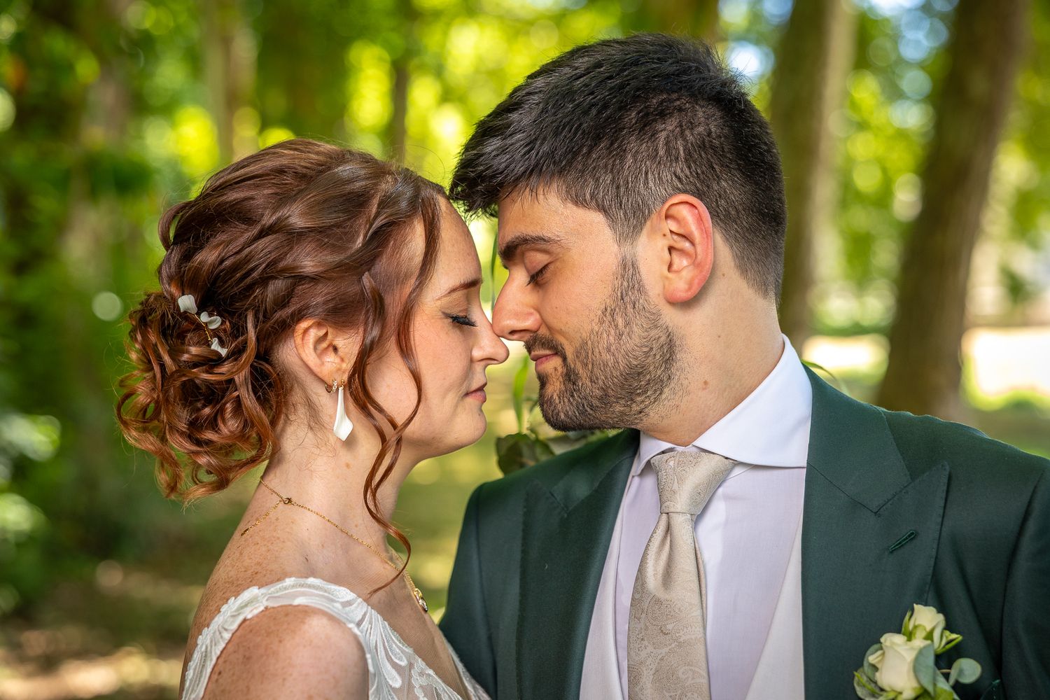 An intimate portrait of a couple in wedding attire sharing a romantic moment outdoors.