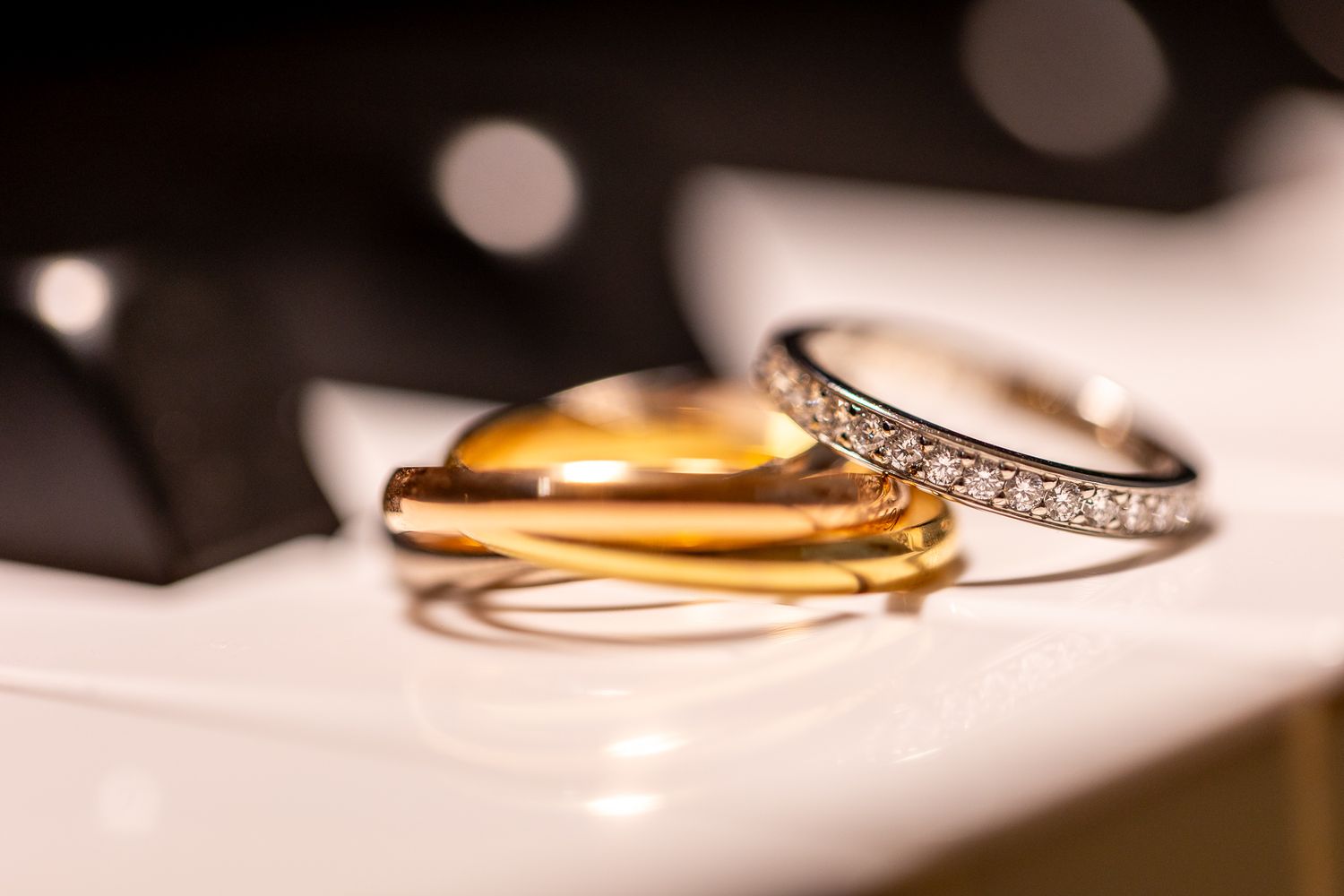 Close-up of elegant wedding rings with diamond details on a white surface.