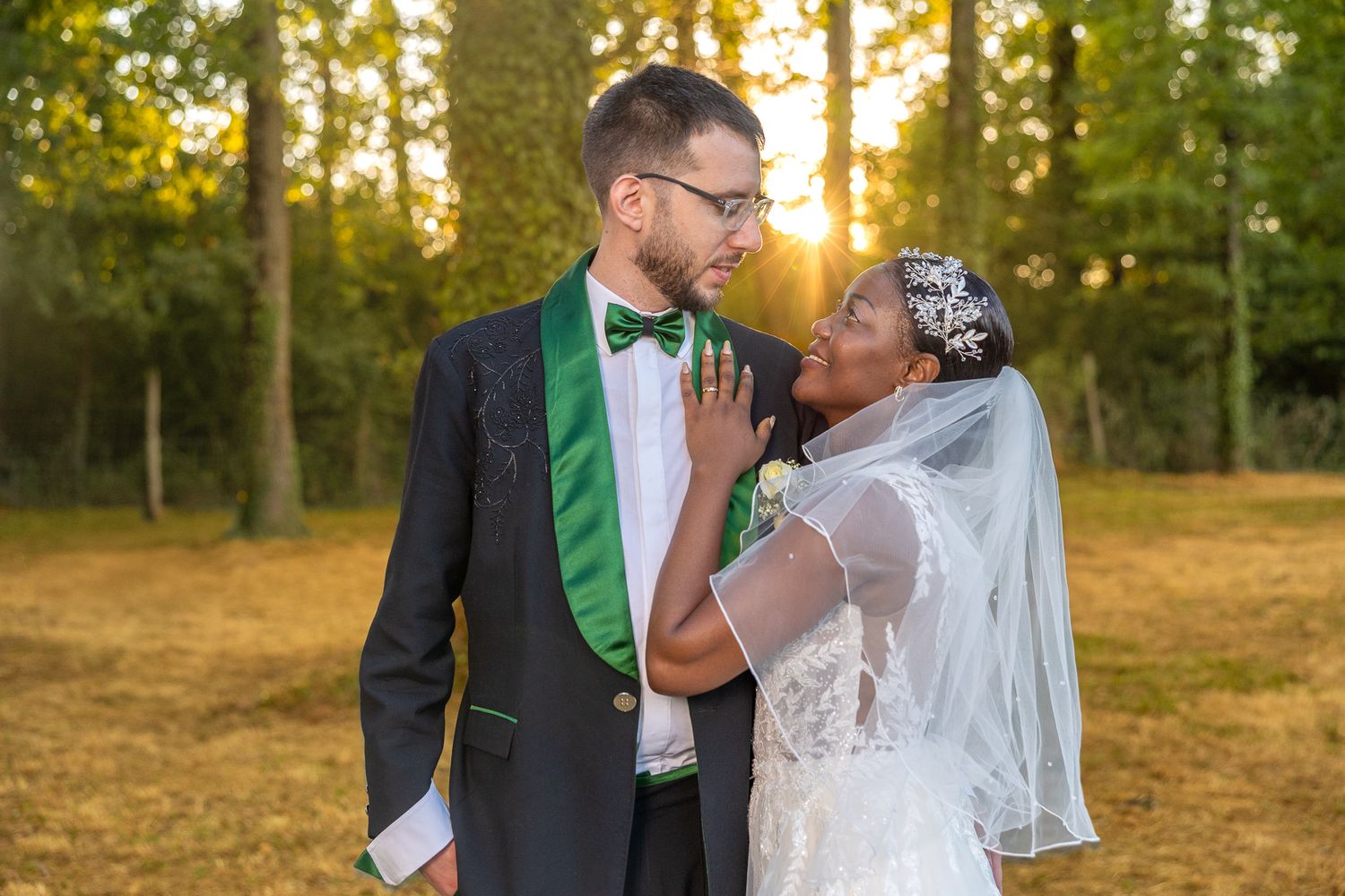 Romantic wedding couple sharing intimate moments at sunset in a wooded outdoor setting.