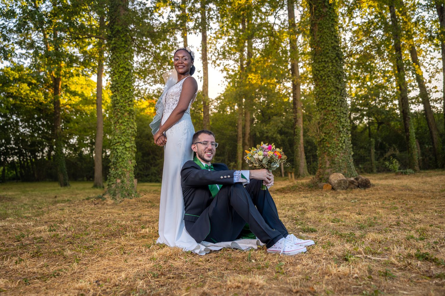 Wedding couple embraces during outdoor photoshoot in golden evening sunlight.
