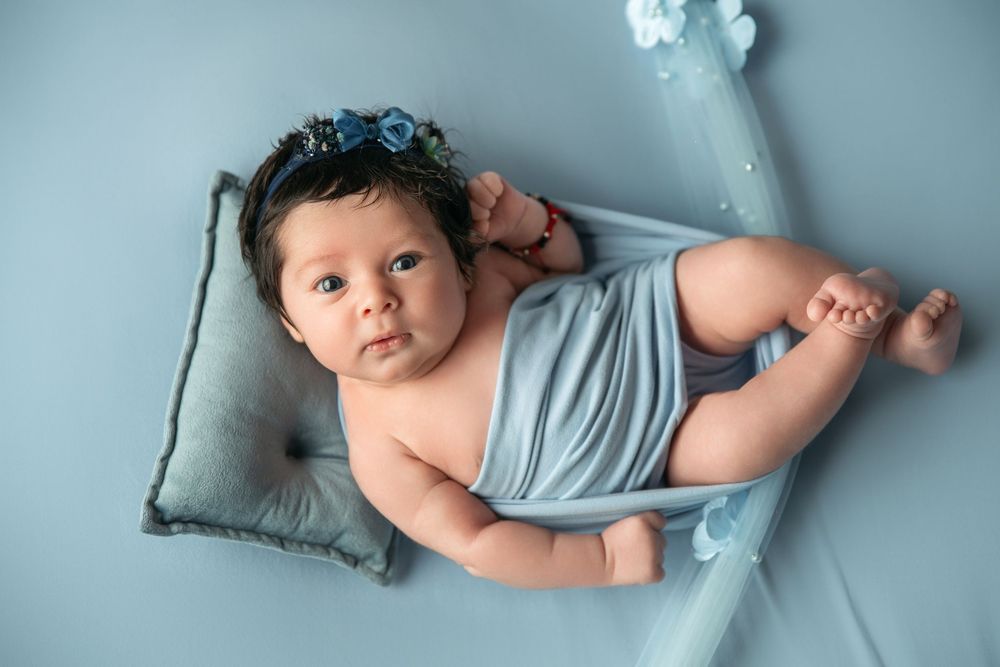Professional newborn photography session with baby posed on blue fabric.