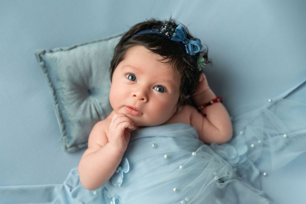 Multiple newborn photography poses captured on light blue bedding with soft lighting.