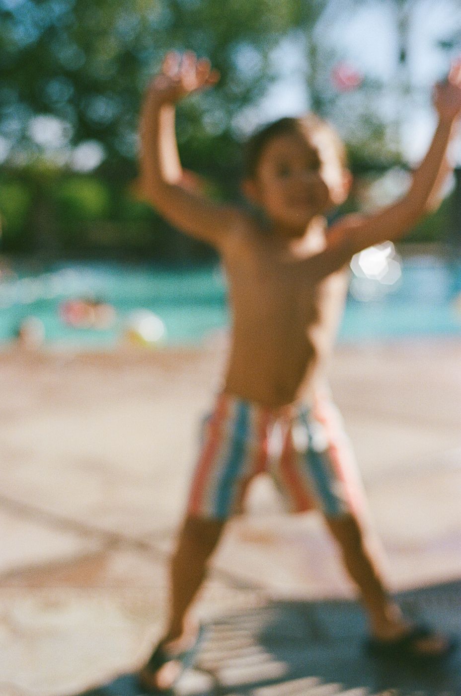 Blurred action shot of summer fun by the pool with palm trees in background.