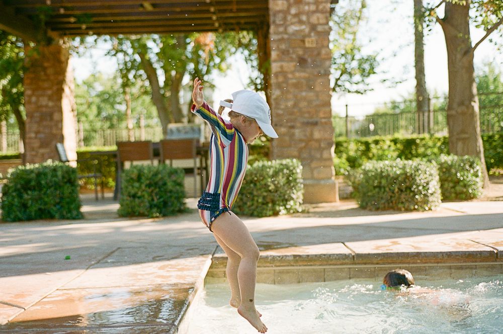 Action shot of jumping into swimming pool on sunny summer day.