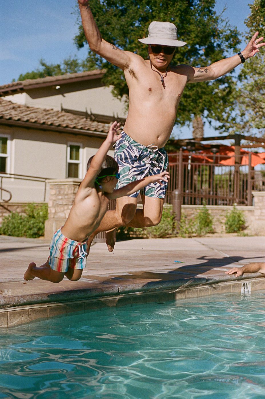 Action sequence of someone jumping into a backyard swimming pool on a bright summer day.