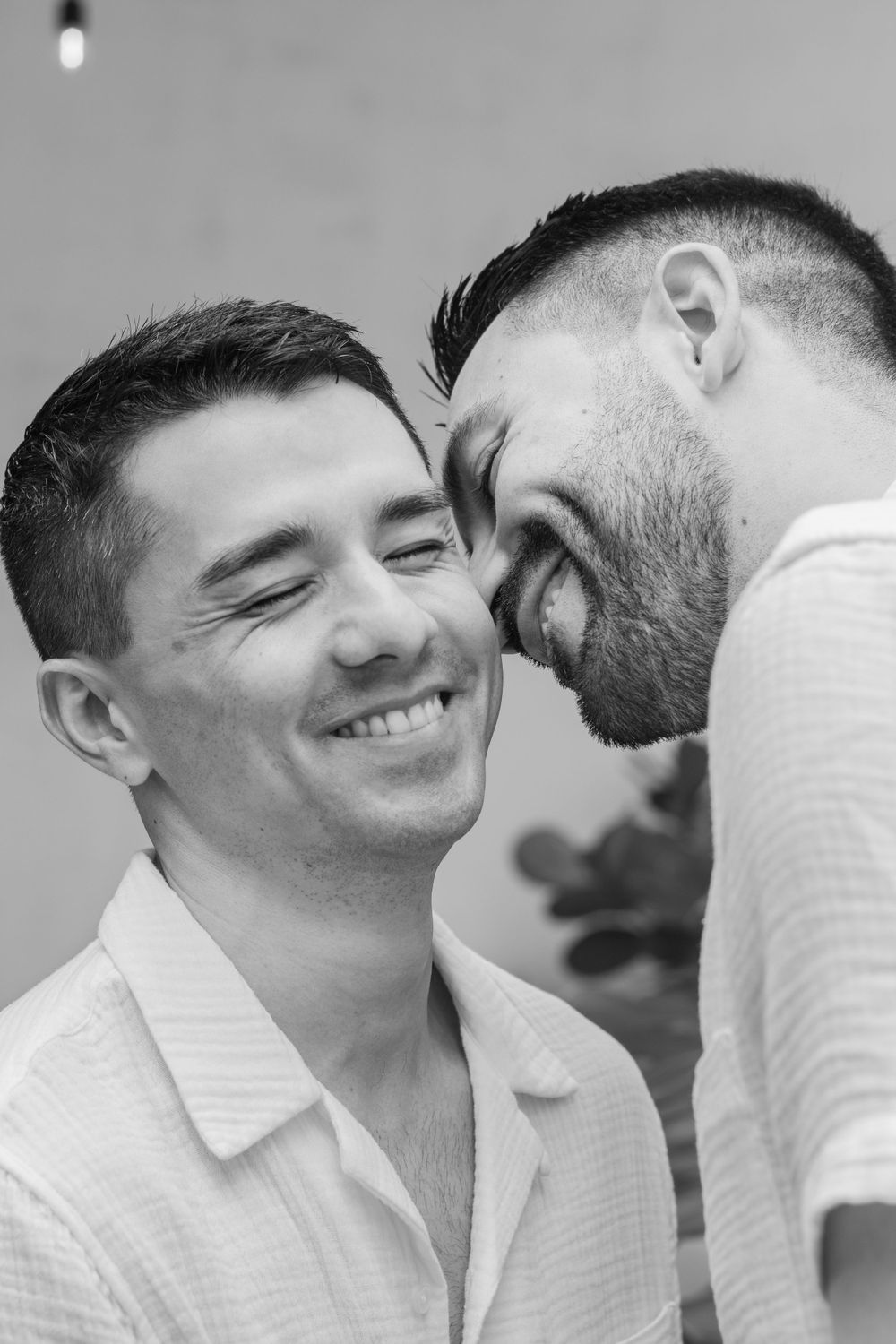 Black and white intimate portrait of couple in white clothing sharing a joyful moment together.