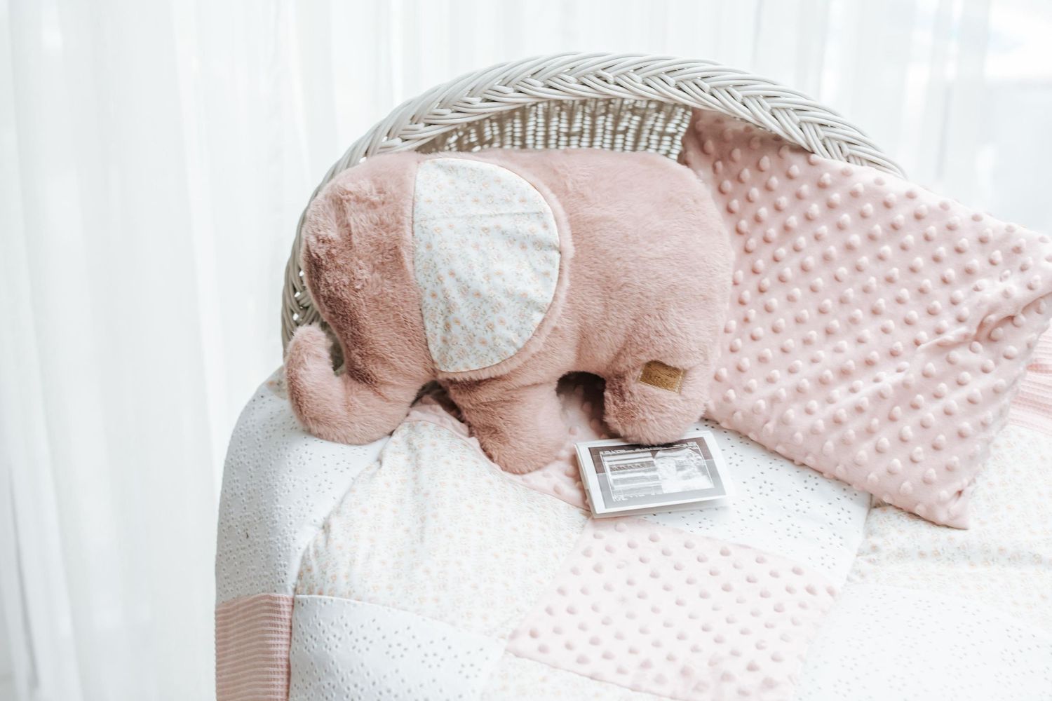 Delicate floral and pastel baby bedding with minky fabric and ribbon details laid out on white surface.