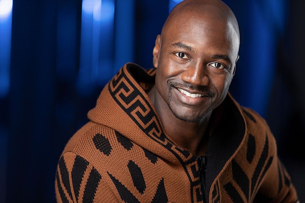Smiling male actor in patterned sweater with dramatic studio lighting, professional Atlanta headshot portrait.