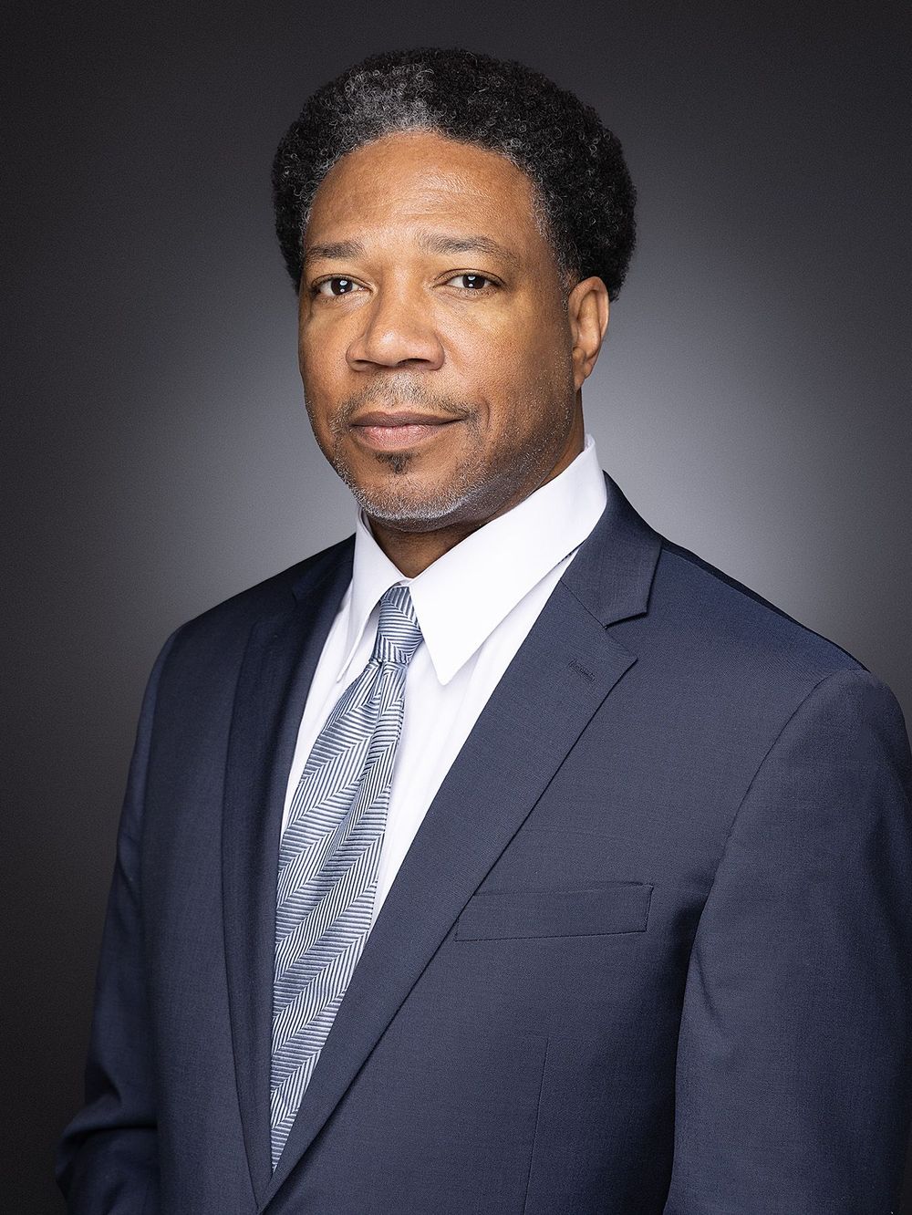 Professional attorney headshot of a man in navy suit and tie against gray background, Atlanta corporate portrait.