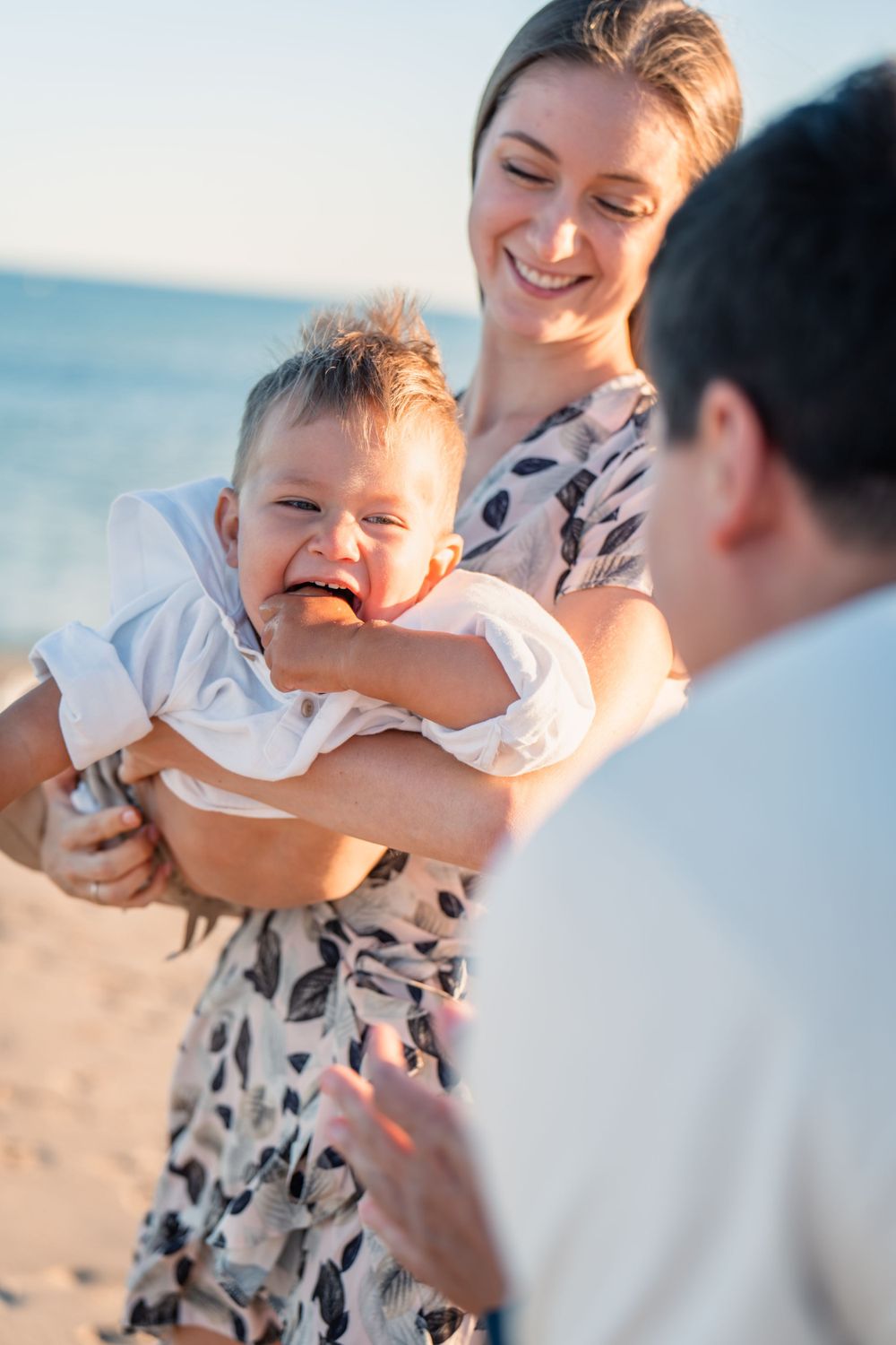 family of 3 playing on the beach for family photos