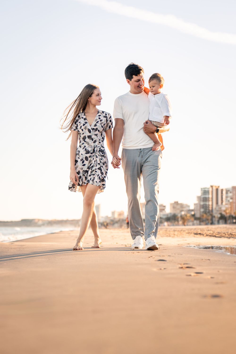 family of 3 walking on sandy beach with fine golden sand