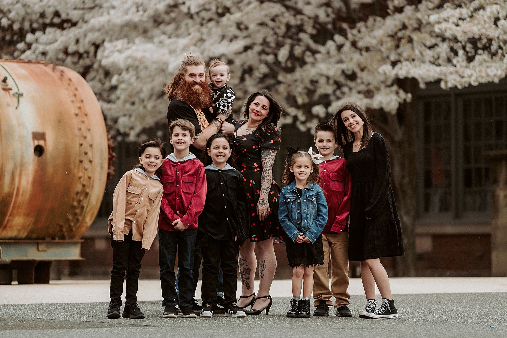 A casual group photo taken outdoors against a rustic backdrop with flowering trees.
