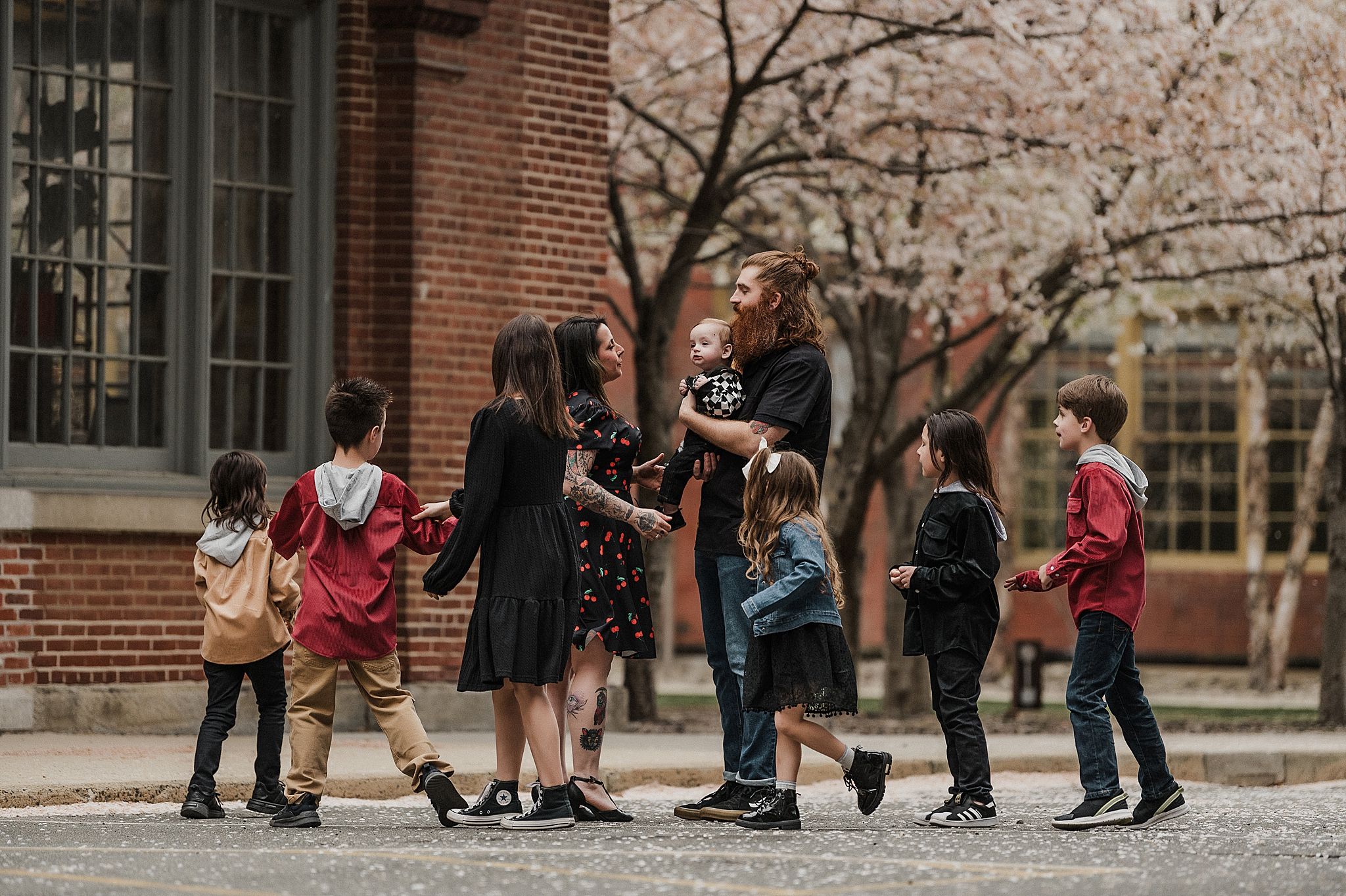 Group gathered outside a brick building with blooming trees in spring.