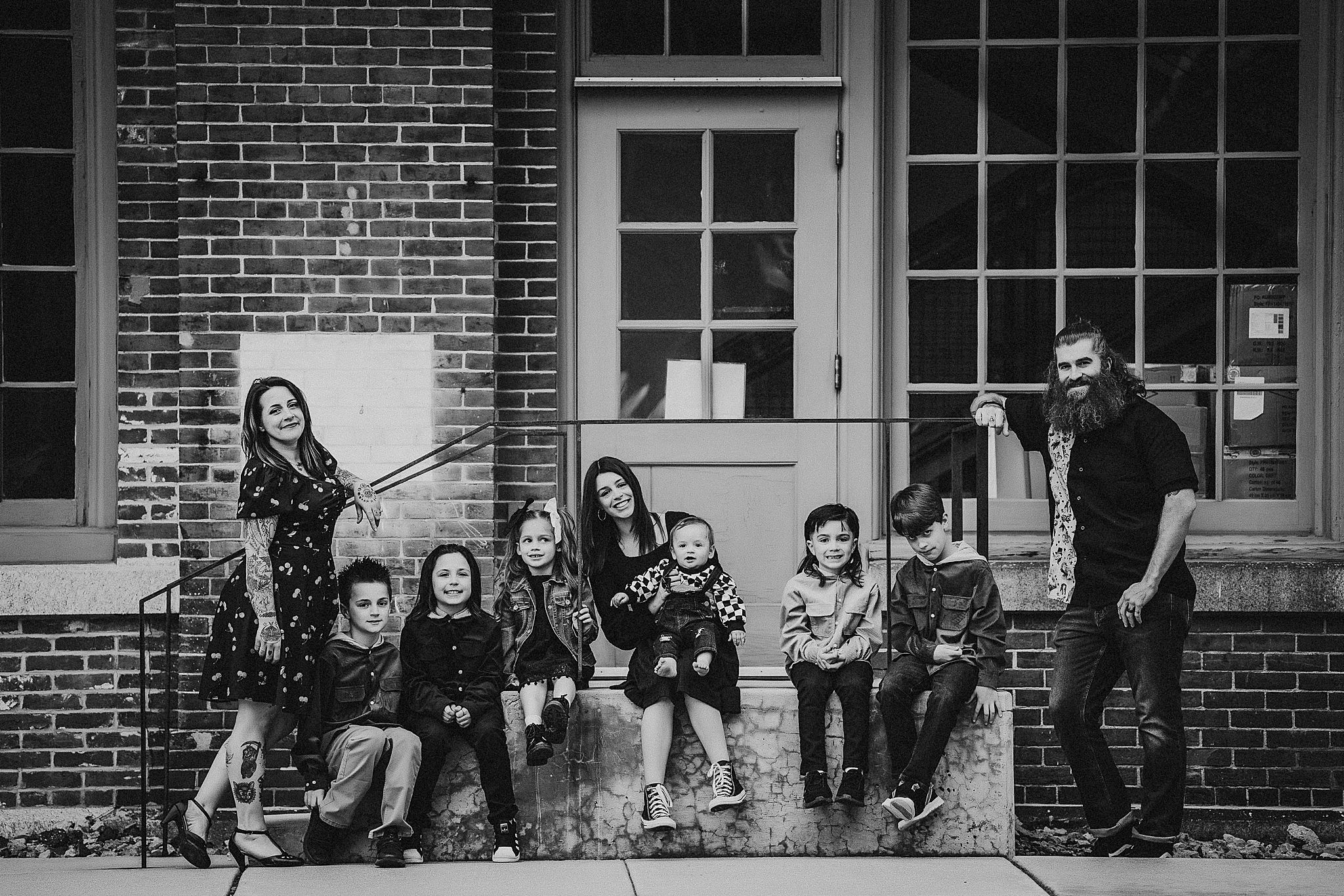 Black and white portrait of group sitting on brick building steps.
