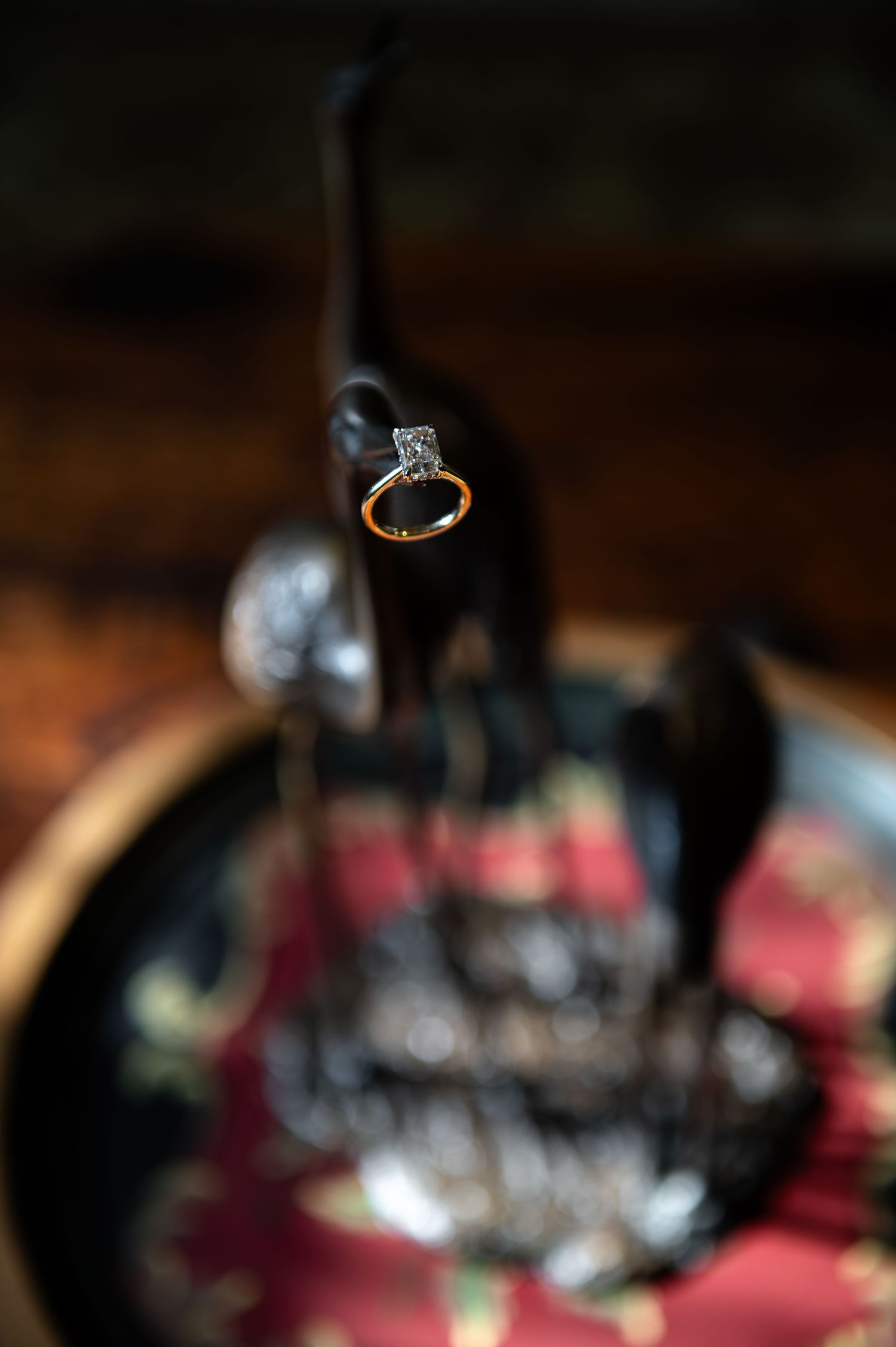Close-up of hands showing an engagement ring against a dress with burgundy sequin floral details.