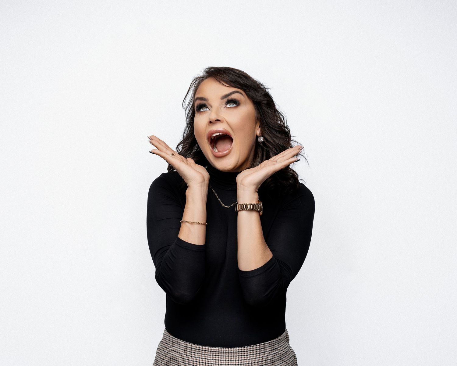 Expressive studio portrait showing excited gesture and surprised expression against white background.