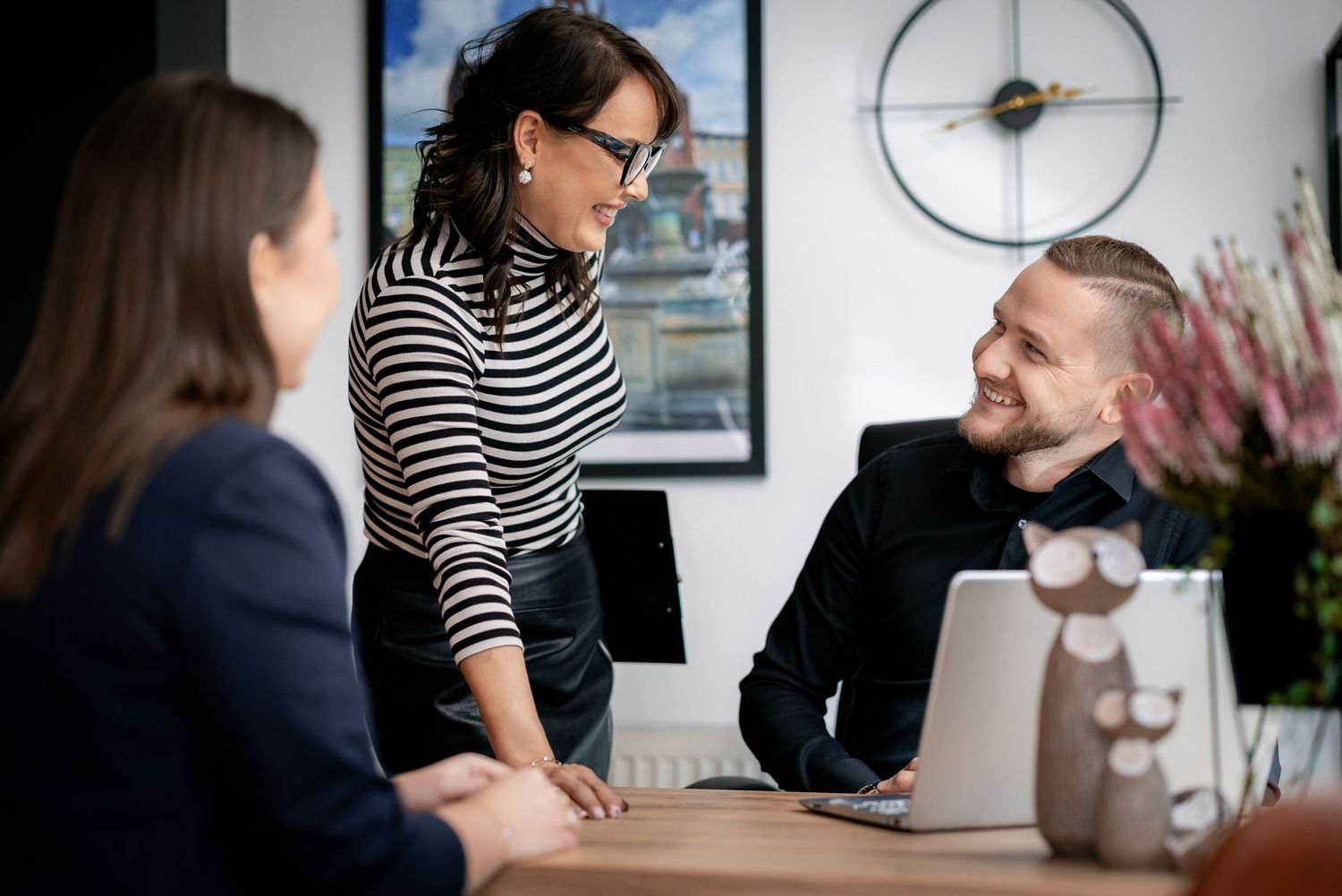 Team members having collaborative discussion around desk in bright office space.