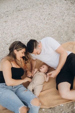 Family lying on blanket outdoors spending time with their baby.