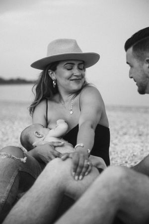 Candid black and white photo of parents sharing tender moment with baby outdoors.