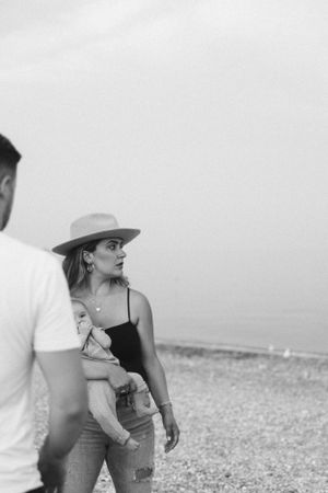 Couple walking along rocky beach shore with infant.