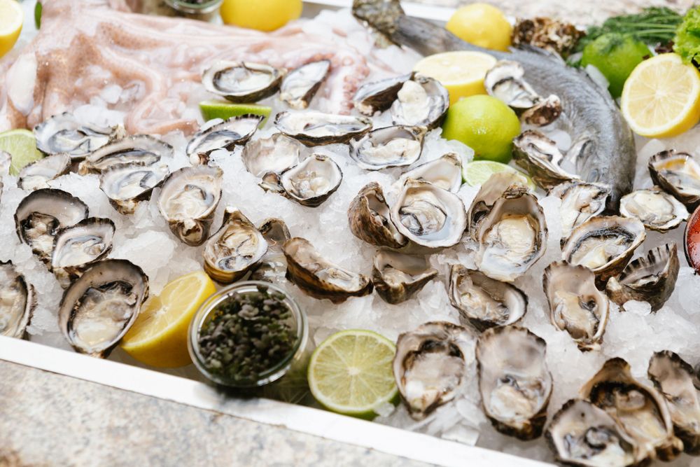 Fresh oysters on ice garnished with lemon wedges and accompaniments.