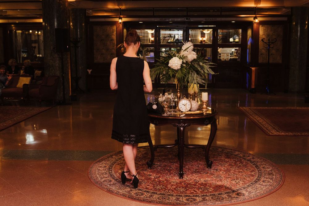 Elegant table with floral arrangement on oriental rug in dark moody venue setting.