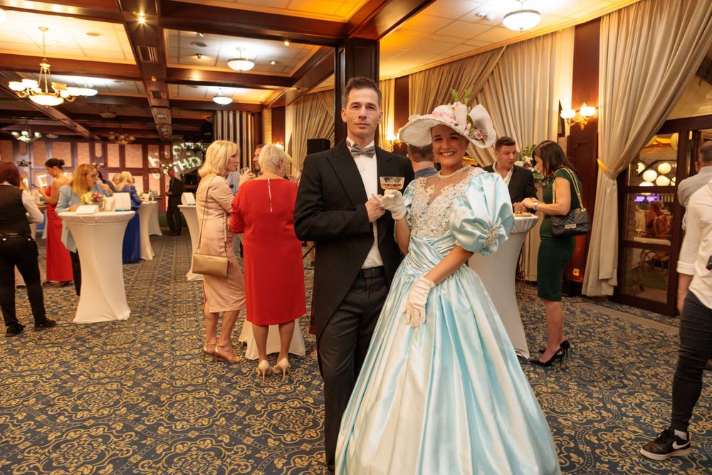 Formal ballroom event with guests dancing and mingling in elegant evening attire.
