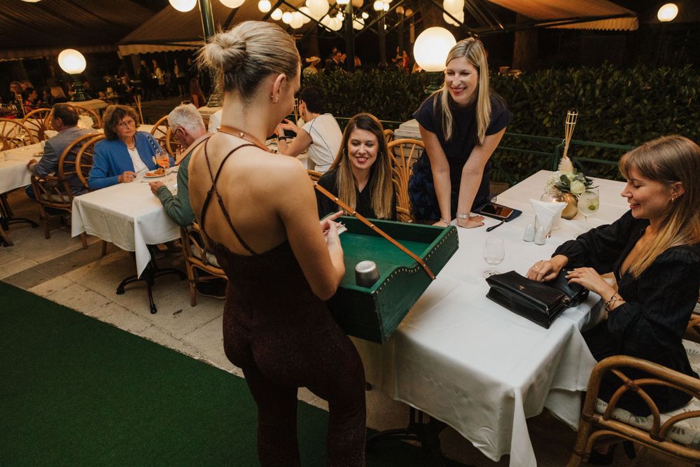 Group gathered around table playing card games at outdoor dining event.
