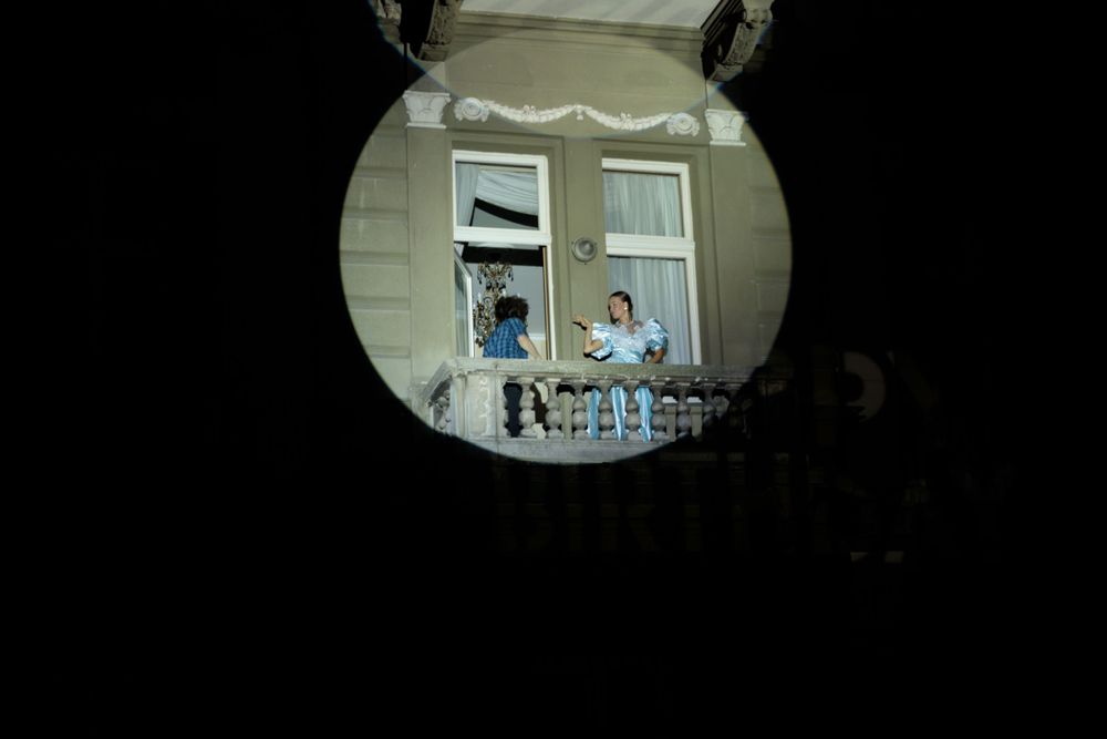 View through circular window frame of people on balcony.