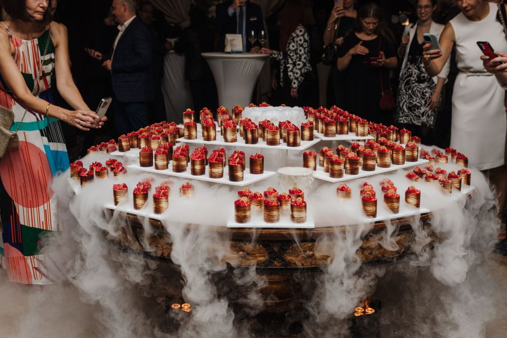 Display of red cocktails on white table with dramatic dry ice smoke effect.