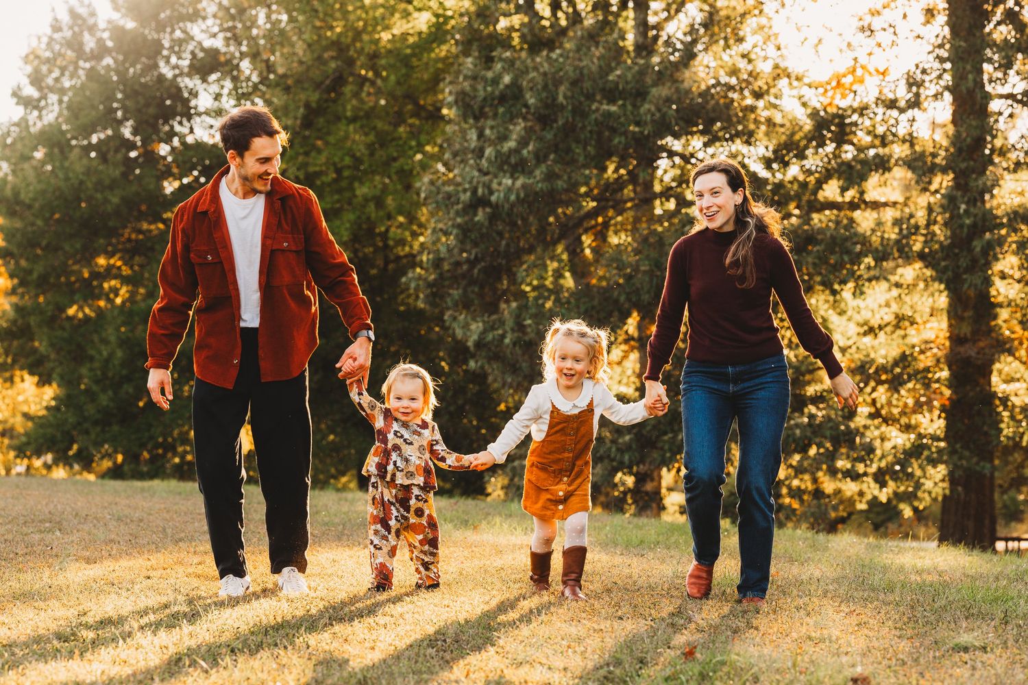 Casual couple portraits in sweaters embracing on coastal grassland during golden hour.