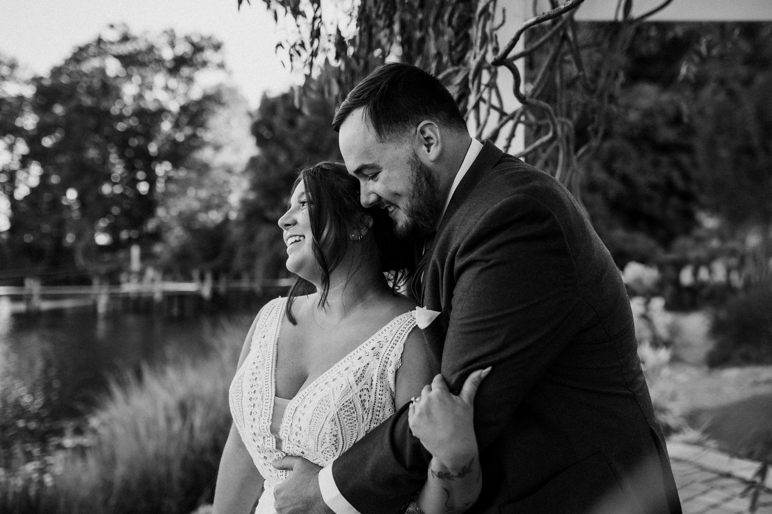 Romantic black and white moment captured between a couple embracing by a tranquil lakeside setting at a micro wedding in newport news, va